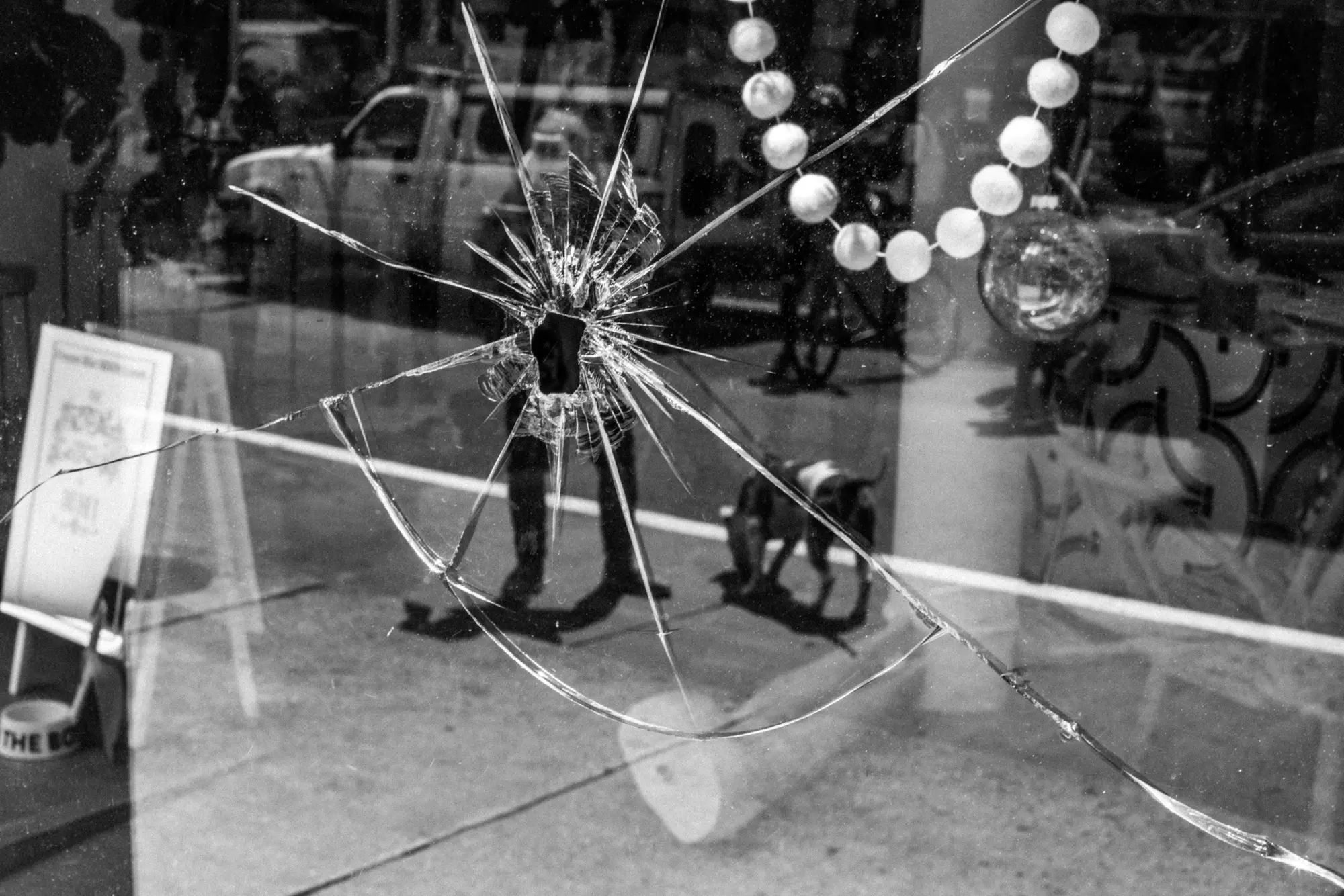 Cracked storefront glass and reflected street