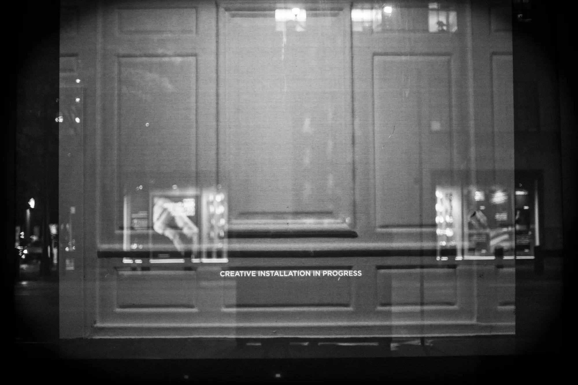 Closed storefront layered with street reflections