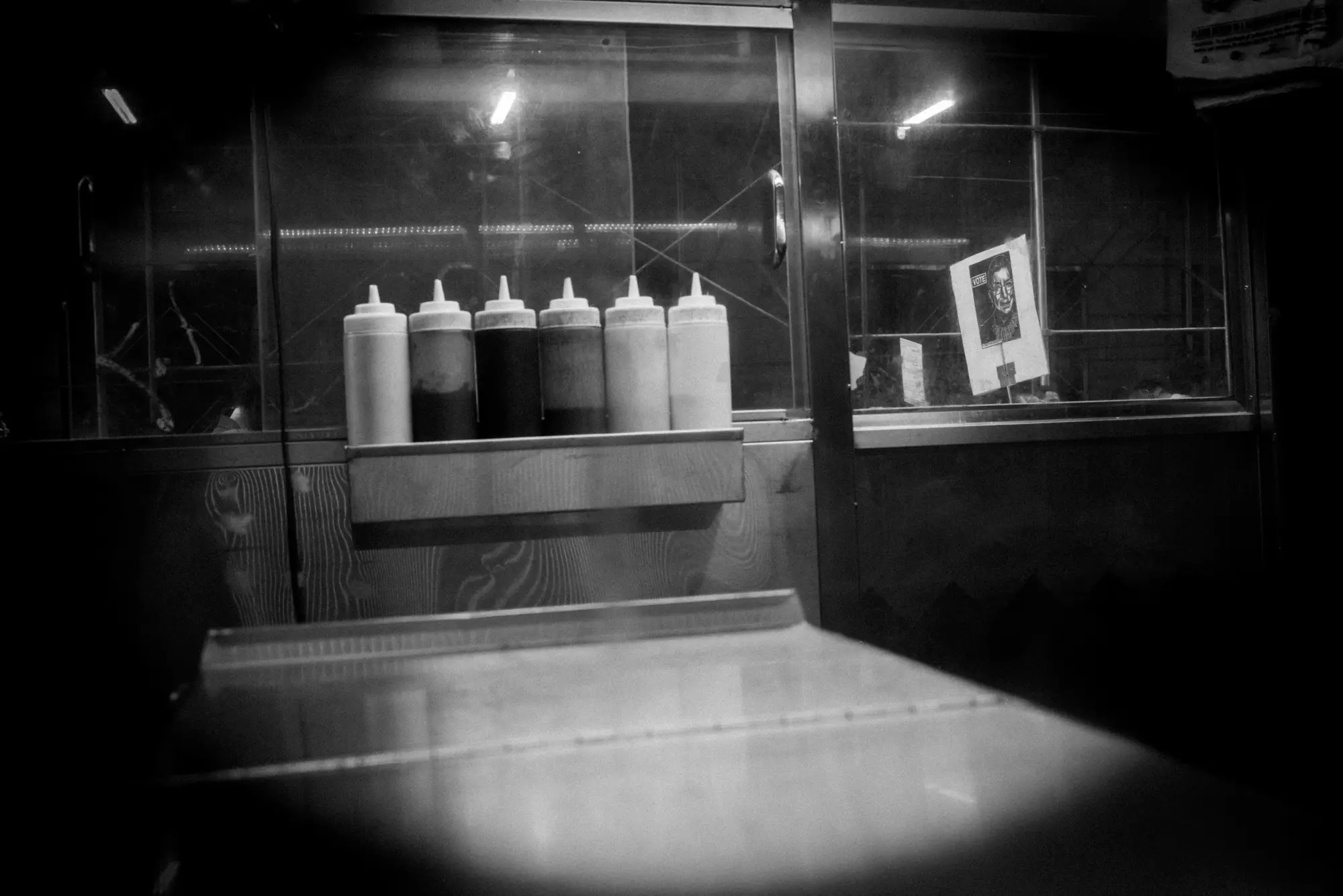 Condiment bottles behind a dark restaurant window