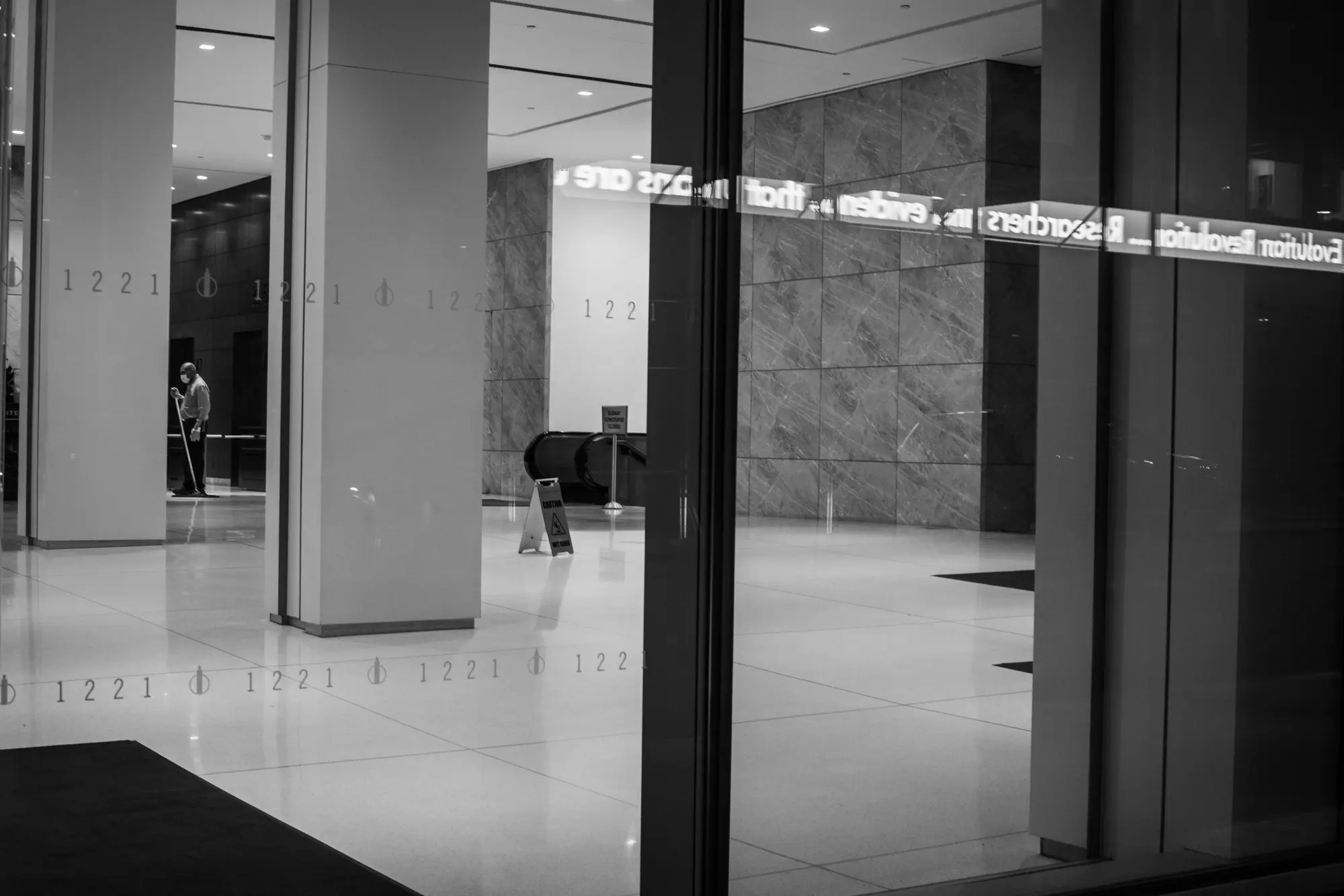 Figures and news ticker reflected in a building lobby