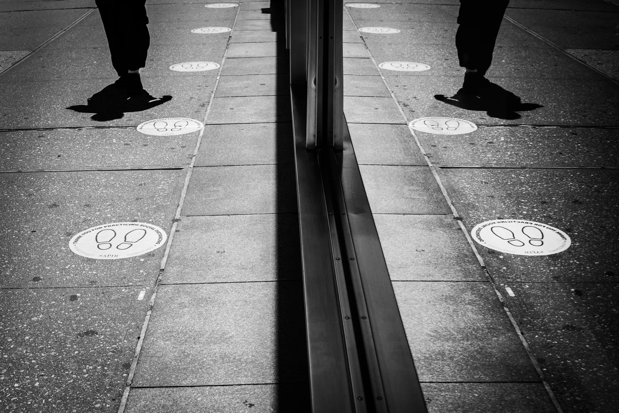 Social distancing markers mirrored on a sidewalk